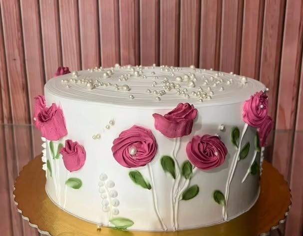 Bolo redondo decorado com rosas em chantilly, feito pelo Cantinho do Sabor