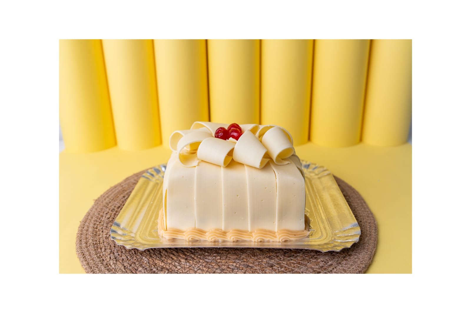 Bolo branco com laços de chocolate produzido pelo Cantinho do Sabor